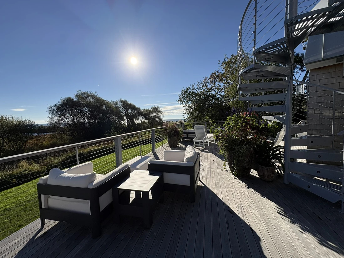Elevated coastal deck with cable railing, lounge seating and water views