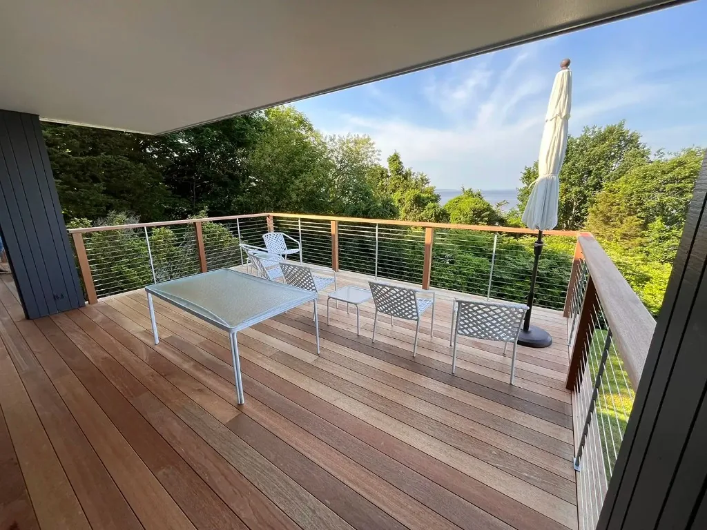 Elevated hardwood deck with cable railing, outdoor seating and a coastal water view