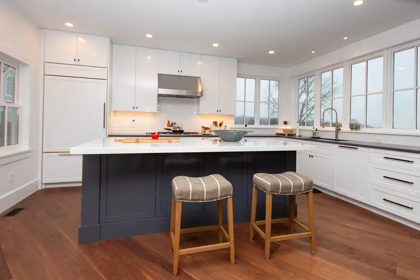 Wide view of the kitchen island with seating and white perimeter cabinets